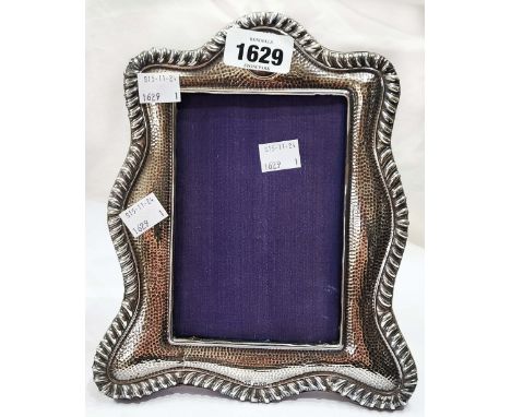An early 20th Century silver fronted photograph frame with decorative border and upholstered easel stand to back - glass miss