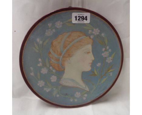 A late 19th Century Mintons Kensington Gore Art Pottery small charger with hand painted decoration, depicting a young lady in