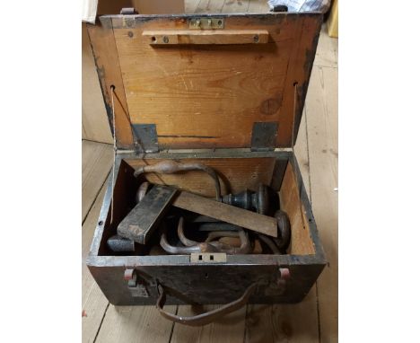 A lift-top wooden box containing a quantity of tools including braces, squares, etc.