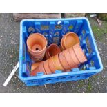A crate containing small terracotta pots and saucers