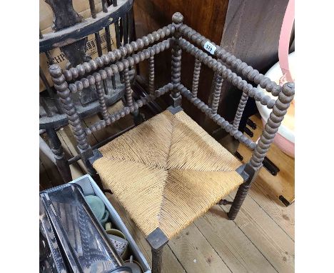 A stained wood bobbin turned corner chair with woven rush seat panel
