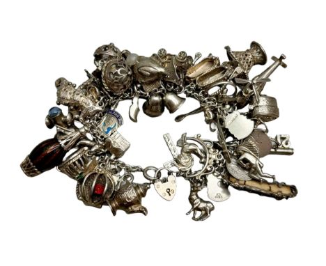A heavy silver charm bracelet with many silver and white metal charms, including a compass, a fish set with a pearl, an artic