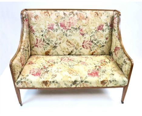 An Edwardian upholstered sofa with swept sides, framed throughout in cross-banded mahogany, raised on squared tapering legs a