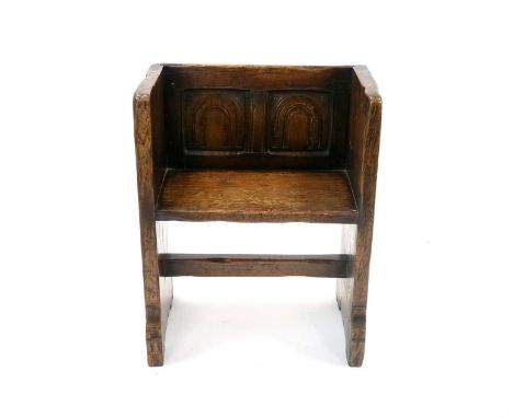 A small old English style carved country oak panelled settle, the back with twin carved arched panels above a thick planked s