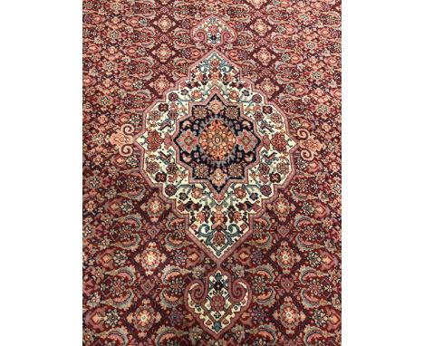 A large Eastern woven wool carpet, the blood red field populated with a central floral medallion and ground decorated with fu