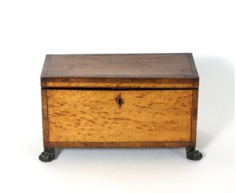 A 19th Century cross-banded burr walnut tea caddy of rectangular form and raised on four brass claw feet, the hinged top open