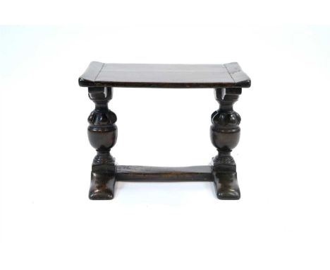A small old English style stained oak twin baluster bench / stool, the planked top with raised sides supported on two heavy t