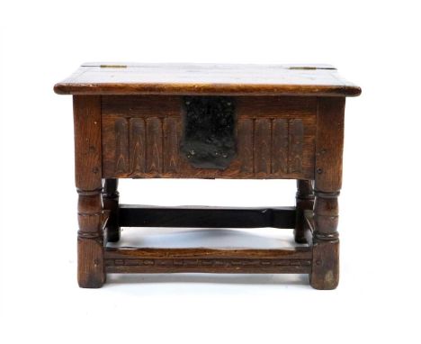 A small old English style country oak box stool, the hinged planked top opening to reveal a hinge interior before a shallow c