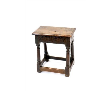 An 18th century English country oak joint stool, the bevelled plank top above a shallow carved frieze decorated with stylised
