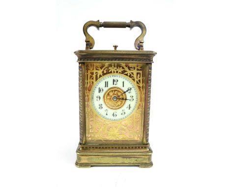 A large Edwardian brass cased carriage clock, with a white porcelain disk dial painted with black Arabic numerals, with etche