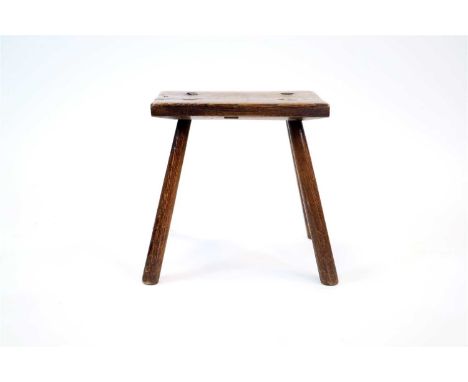 An old English oak milking stool, the thick cut planked top raised on four simple tapering turned legs, 33 cm high, the top m