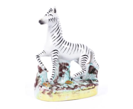 A Staffordshire pottery model of a zebra, circa 1870, naturalistically modelled on a tree stump sprigged oval base, 15cm high