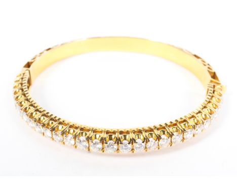 An unmarked yellow metal and diamond bangle half set with single line  of 28 diamonds. 25g. (to test)