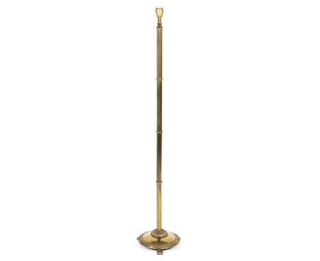 A brass standard lamp, 20th century, with reeded column on gadrooned circular base with scroll feet, fitted for electricity, 