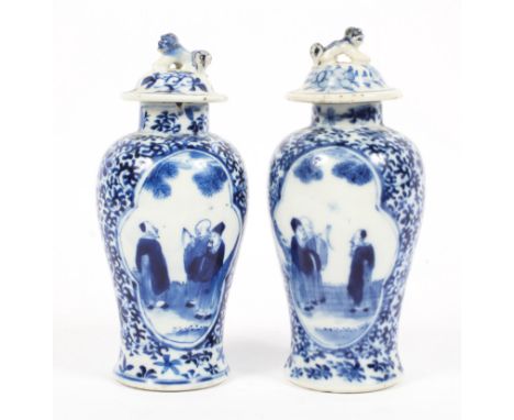 A pair of 19th century blue and white lidded vases decorated with two groups of scholars reserved on a floral patterned groun