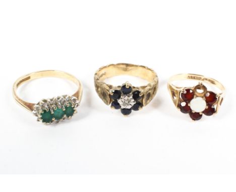 Three 9ct gold rings. A three stone emerald and diamond ring, an opal and garnet ring (one vacant garnet) and a sapphire and 