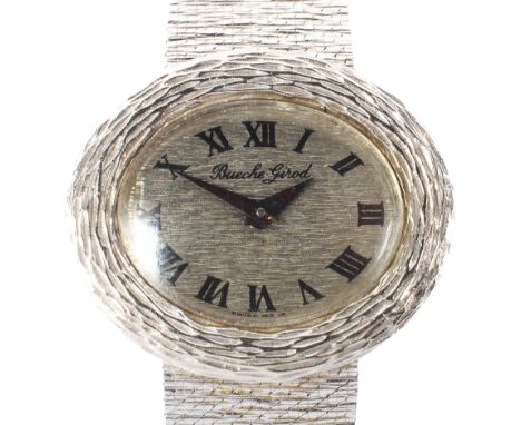A Ladies Beuche Girod 18ct white gold manual wind wristwatch. Silver oval face with Roman numeral batons to a textured bezel 
