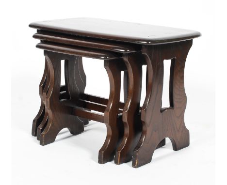 A nest of Ercol dark elm occasional tables, of shaped rectangular form, on pierced shaped supports, bearing blue label, 42.5c