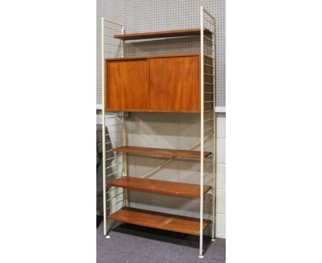 A set of Staples Ladderax shelving unit. with white ladder supports and a hanging teak cabinet with sliding doors, glass shel