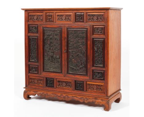 A Chinese carved hardwood cabinet, 20th century, the panelled front densely carved with dragons, flowers, scrolls, with fishe