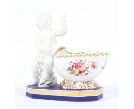 A Coalport figural inkstand, circa 1825, mounted with a white biscuit figure of Cupid astride a shell, before a shell-shaped 