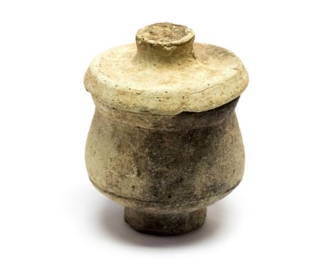 A small Roman white ware pot with a narrow base and a flat knopped lid. It is 91 mm high by 68 mm in diameter and was found i