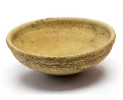 Roman pottery dish of a light cream colour. It is 126 mm diameter and 44 mm high. It is undecorated with a small lip around t
