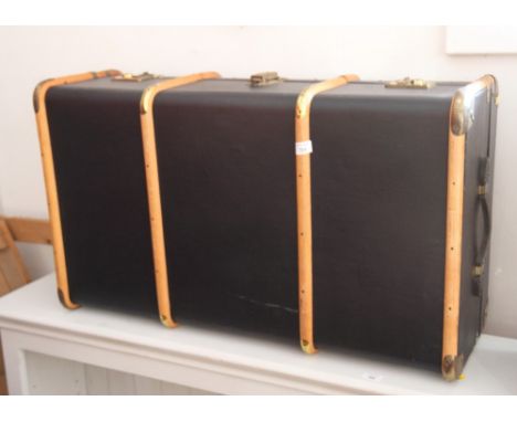 A wood bound travel trunk with leather carry handles