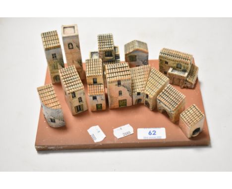 A set of mediterranean styled model ceramic houses on a terracotta base, each building being independent and movable to anoth