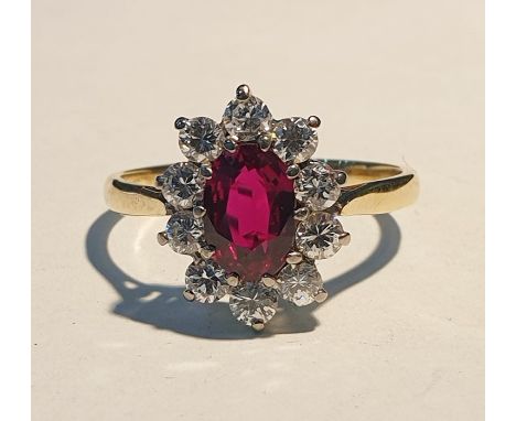 Yellow metal, ruby and diamond cluster ring set centre oval facet-cut ruby and having surround of 10 diamonds, 15mm x 10mm ov