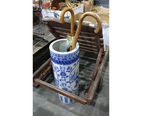 Large ceramic blue and white Chinese style umbrella stand/stick stand containing a walking stick and three umbrellas and one 