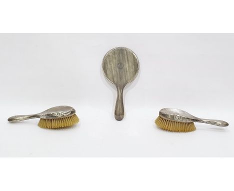Three piece silver-backed dressing table set with engine-turned decoration and monogram, comprising pair of hairbrushes and a