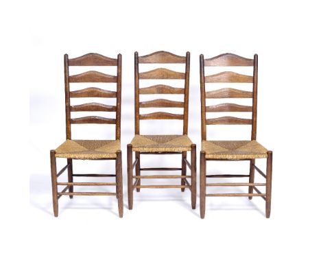 Manner of Ernest Gimson Three oak Clissett chairs, with ladder back and rush seats, circa 1900, each 107cm high