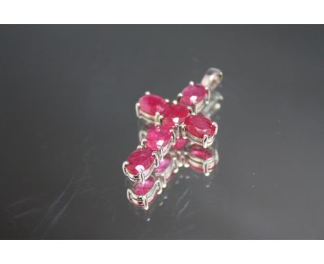A HALLMARKED 9 CARAT WHITE GOLD CROSS, set with six oval ruby type stones, H 3.5 cm