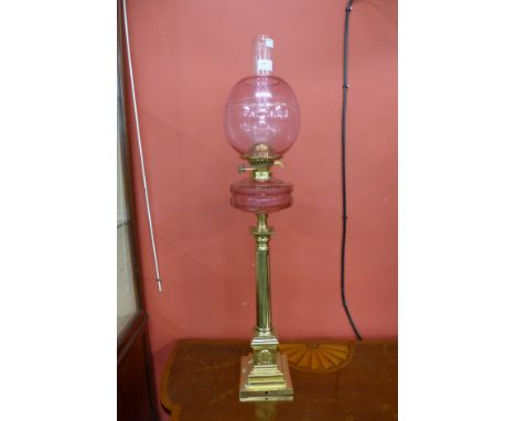 An early 20th Century brass and cranberry glass oil lamp