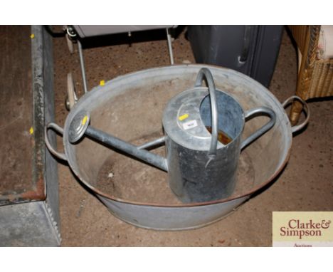 A galvanised bath drilled out as a planter; and a galvanised watering can with rose 