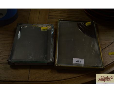 A small brass framed mirror and another metal bevel edged framed mirror