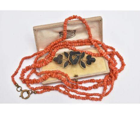 A CARVED BOG OAK BROOCH AND A CORAL BEAD NECKLACE, the brooch in the form of a harp and shamrocks, in a base metal mount with