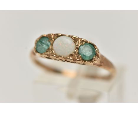 A 9CT GOLD OPAL AND EMERALD RING, set with a central circular opal cabochon, flanked with two circular cut emeralds, open wor