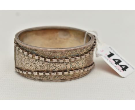 A LATE VICTORIAN SILVER HINGED BANGLE, engraved ivy leaf detail, with a raised scallop pattern, hallmarked Birmingham 1883, s