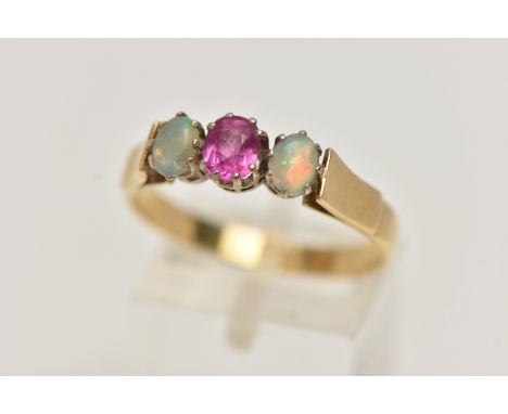 A RUBY AND OPAL RING, a principle set oval cut ruby, set with two oval opals, prong set in yellow metal, leading on to a yell