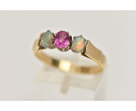 A RUBY AND OPAL RING, a principle set oval cut ruby, set with two oval opals, prong set in yellow metal, leading on to a yell