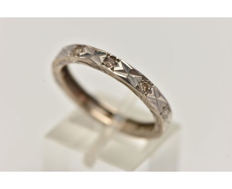 A WHITE METAL AND DIAMOND ETERNITY BAND RING, a flat profile band with a diamond cut pattern to the top and sides, grain set 