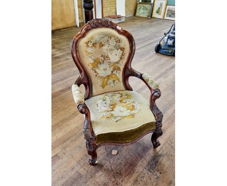 A VICTORIAN WALNUT SHOW-WOOD FRAME ARMCHAIR upholstered in floral tapestry, carved open arms, raised on cabridle legs and cas