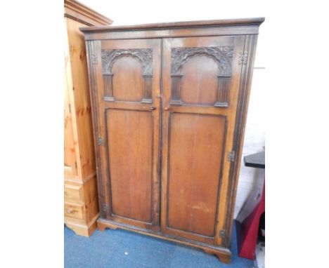 An oak double wardrobe, the outswept pediment over two carved panelled doors, raised on bracket feet, 125cm x 56cm x 183cm.