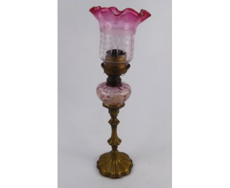 A W & W Kosmos brass and glass candlestick oil lamp, with painted floral reservoir and etched shade with cranberry frill, 49c