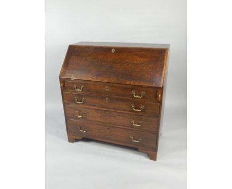 A George III oak bureau, the fall flap opening to reveal a cupboard, semi secret compartments, drawers and recesses, over fou