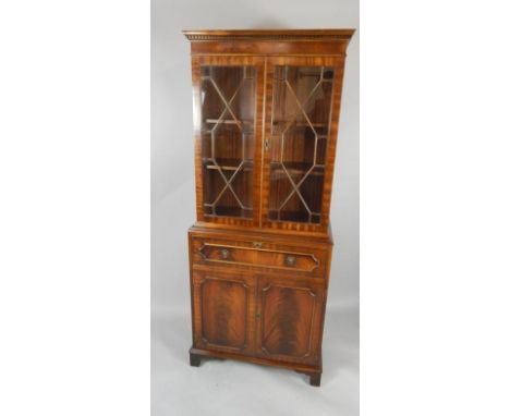 A Reprodux mahogany secretaire bookcase, the dentil moulded pediment over two glazed doors enclosing two shelves, above a sec