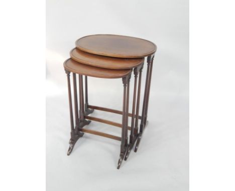 A nest of oval mahogany occasional tables, raised on slender turned supports, raised on bracket feet, largest, 52cm x 37cm x 