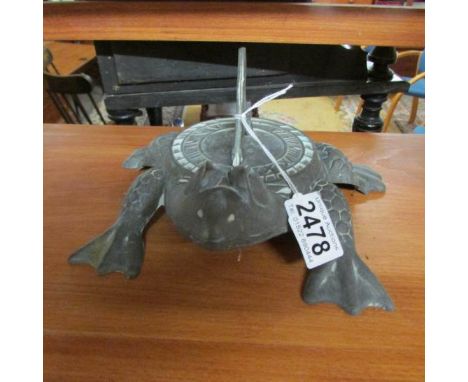 A verdigree brass sundial in the shape of a frog.